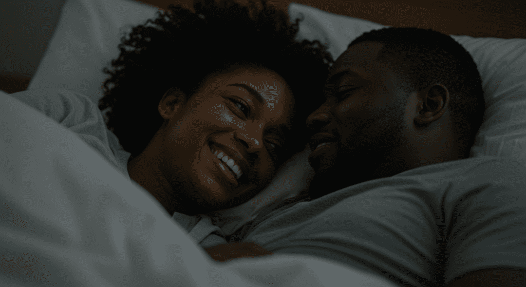 Un homme et une femme noirs au lit, et la femme sourit.