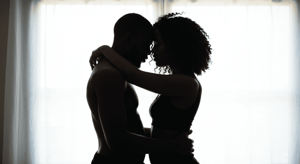 Silhouetted couple embracing intimately in a loving and consensual sexual encounter, focusing on connection and closeness.