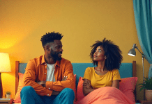 Frustrated man sitting on the edge of a bed while his partner stares at the ceiling, looking bored—symbolizing dissatisfaction during sex.